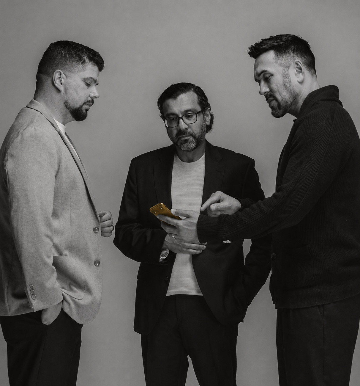 Three Renovo House operators reviewing a phone in a studio