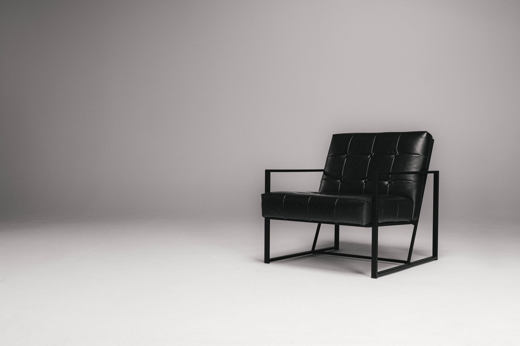 A single black leather armchair in a light studio